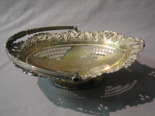 A boat shaped pierced silver plated cake basket with swing handle, raised on an oval foot