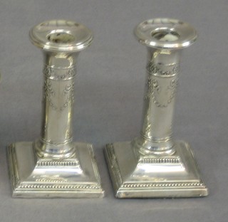 A pair of Edwardian embossed silver candlesticks with swag decoration, raised on square feet 4", Birmingham 1906