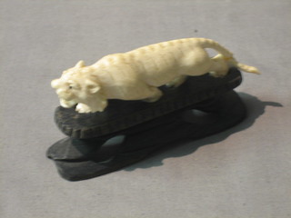 A carved ivory figure of a walking tiger on a hardwood base, (tail f)