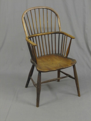 A 19th Century elm and comb back kitchen carver chair, raised on turned supports with an H framed stretcher (some old worm)