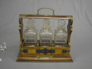 An oak and silver plated tantalus with 3 cut glass decanters (some damage to the decanters and no key)