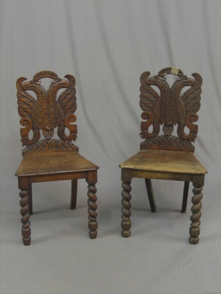 A pair of 19th Century Continental carved oak hall chairs, the backs decorated double eagles with solid seats, raised on spiral turned supports