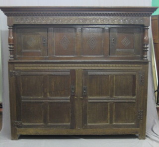 An 18th Century carved oak court cupboard, the upper section with moulded dentil cornice and carved frieze, fitted cupboards enclosed by 2 panelled doors, the base fitted a cupboard enclosed by 2 large panelled doors with wrought H framed hinges 70"