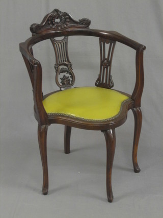 An Edwardian carved mahogany tub back chair with carved cresting rail and pierced splat back, the seat upholstered in green rexine, raised on cabriole supports