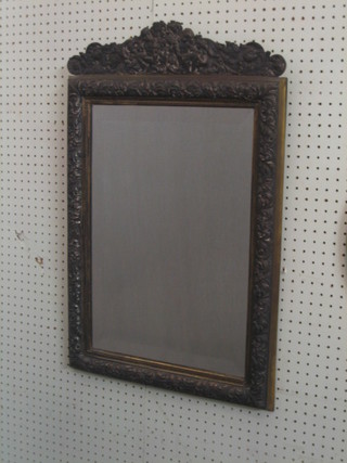 A rectangular bevelled plate mirror contained in a heavily embossed silver plated frame 29" x 19"