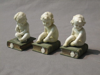 3 19th Century biscuit porcelain figures of seated infants on books 3"