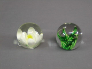 A glass paperweight decorated a flower and 1 other
