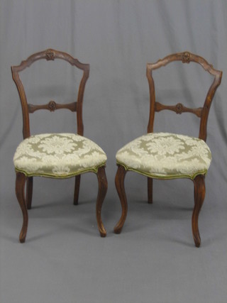 A pair of Victorian carved walnut spoon back dining chairs with carved mid rails, seats of serpentine outline, raised on cabriole supports