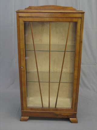 A 1930's Art Deco walnut display cabinet, the interior fitted adjustable shelves enclosed by a sunburst panelled door, raised on ogee bracket feet 23"