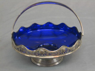 A circular pierced silver plated cake basket with wavy rim and blue glass liner 8 1/2"