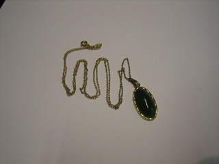 A gold pendant set a cabouchon cut green hardstone hung on a gold chain