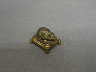 A 19th Century gilt metal pin cushion in the form of a seated hedgehog, raised on a cushion 1 1/2"