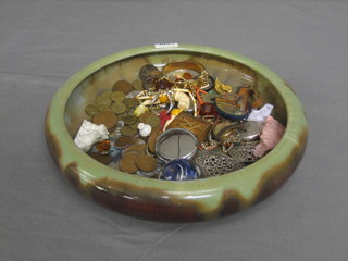 A green glazed bowl containing a collection of various coins, costume jewellery etc