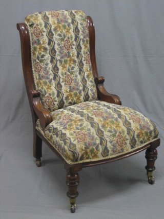 An Edwardian mahogany show frame nursing chair upholstered in striped material raised on turned supports