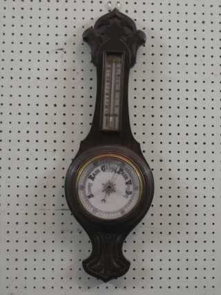 An aneroid wheel barometer and thermometer with porcelain dial contained in a carved oak case
