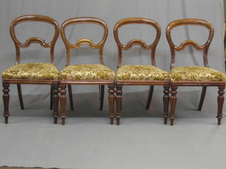 A set of 4 Victorian walnut balloon back dining chairs with shaped mid rails and upholstered drop in seats, raised on turned and reeded supports (some old worm)