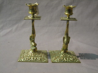 A pair of brass candlesticks supported by dolphins 4 1/2"