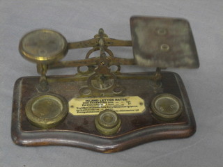 A pair of metal postage scales, raised on oak base complete with weights
