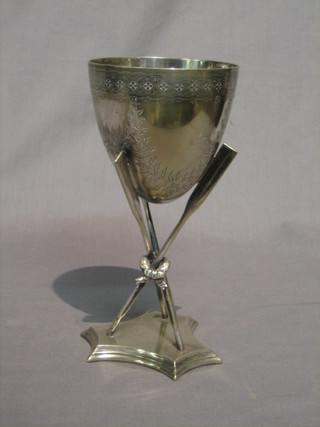 A Victorian silver plated goblet shaped rowing trophy supported by 3 oars and raised on a triform base