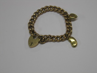 A hollow 9ct gold curb link bracelet hung 2 charms and a padlock clasp