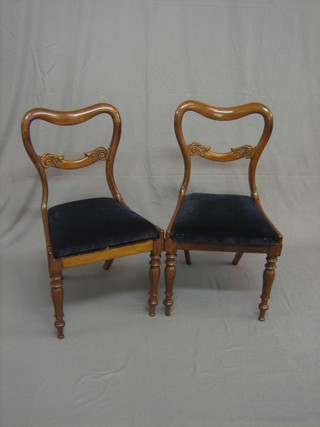 A pair of Victorian mahogany spoon back dining chairs with carved mid rails and upholstered drop in seats, on turned supports