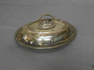 An oval silver plated entree dish and cover with bead work border