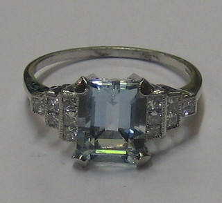 A lady's 18ct white gold dress ring set a rectangular cut aquamarine supported by 12 diamonds