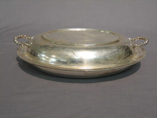 An oval twin handled silver plated entree dish and cover with bead work borders