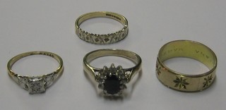 A gold coloured wedding band and 3 dress rings