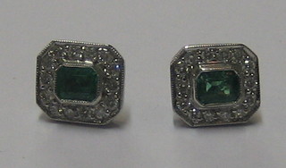 A pair of lady's white gold earrings set lozenge cut emeralds surrounded by diamonds