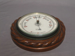 An Edwardian aneroid barometer with porcelain dial contained in a carved oak case 11"