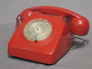 A red plastic dial telephone, the base marked 746 GEN 80/2