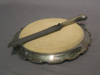 A circular silver plated bread board holder by Walker & Hall and a bread knife