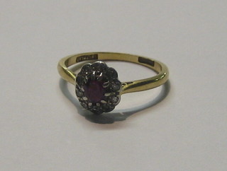 A lady's gold dress ring set an oval cut red stone surrounded by diamonds