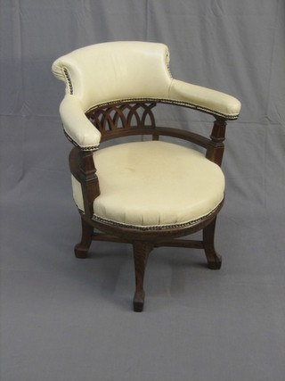 A Victorian oak revolving office chair upholstered in white hide, raised on square supports