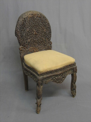 A pierced and carved Burmese hardwood chair with arch shaped back and upholstered seat, raised on carved supports