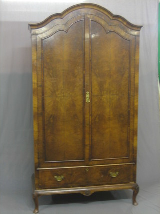 A 1930's Queen Anne style walnut dome shaped wardrobe enclosed by panelled doors, the base fitted a drawer and raised on cabriole supports, 42" wide