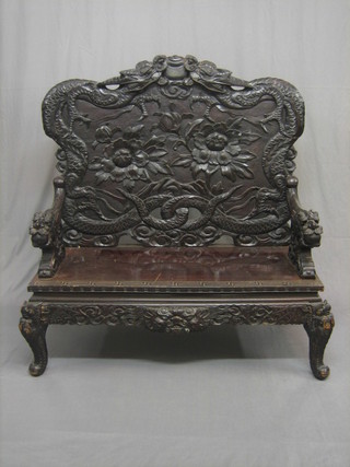 An Eastern carved hardwood settle with raised back, craved dragons throughout, raised on cabriole supports 50"