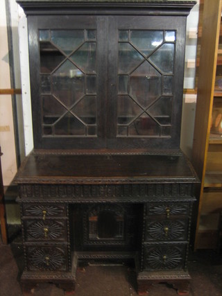 A Victorian carved oak bureau bookcase, the upper section with moulded cornice fitted adjustable shelves enclosed by astragal glazed panelled doors, above a kneehole pedestal desk fitted a cupboard with arched panelled doors above 6 long drawers 42"