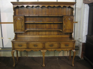 A 20th Century Georgian style honey oak dresser with  moulded cornice, the raised back fitted shelves, the base fitted 4 long drawers and raised on cabriole supports 68"
