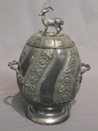 A Victorian embossed Britannia metal oval twin handled biscuit barrel and cover, raised on a circular spreading foot, the finial in the form of a stag 11"