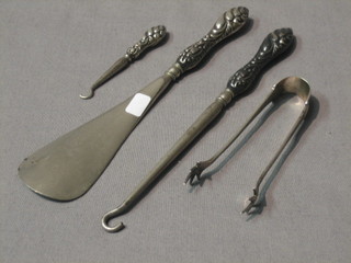 A silver handled shoe horn, 2 button hooks and a pair of silver tongs