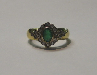A lady's gold dress ring set an oval cut emerald surrounded by numerous diamonds