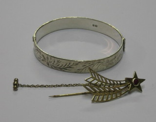 A gold shooting star pin and a silver bangle