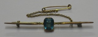A gilt metal bar brooch set a blue stone