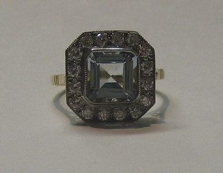 A lady's 18ct gold dress ring set a square cut aquamarine surrounded by numerous diamonds