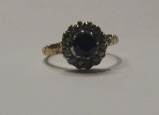 A lady's 18ct gold dress ring set a circular cut sapphire surrounded by numerous diamonds