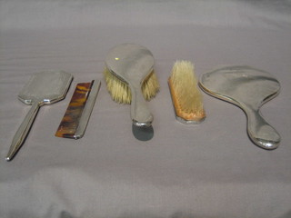 A  silver  backed  hand  mirror,  matching  hair  brush,  a   silver backed hand mirror (f), matching clothes brush and comb