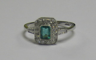 A  lady's 18ct white gold dress ring set a rectangular cut emerald surrounded by diamonds