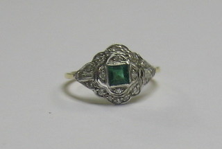A lady's 18ct gold dress ring set a square cut emerald surrounded by numerous diamonds